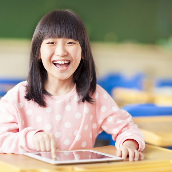 a young girl smiling while using a tablet