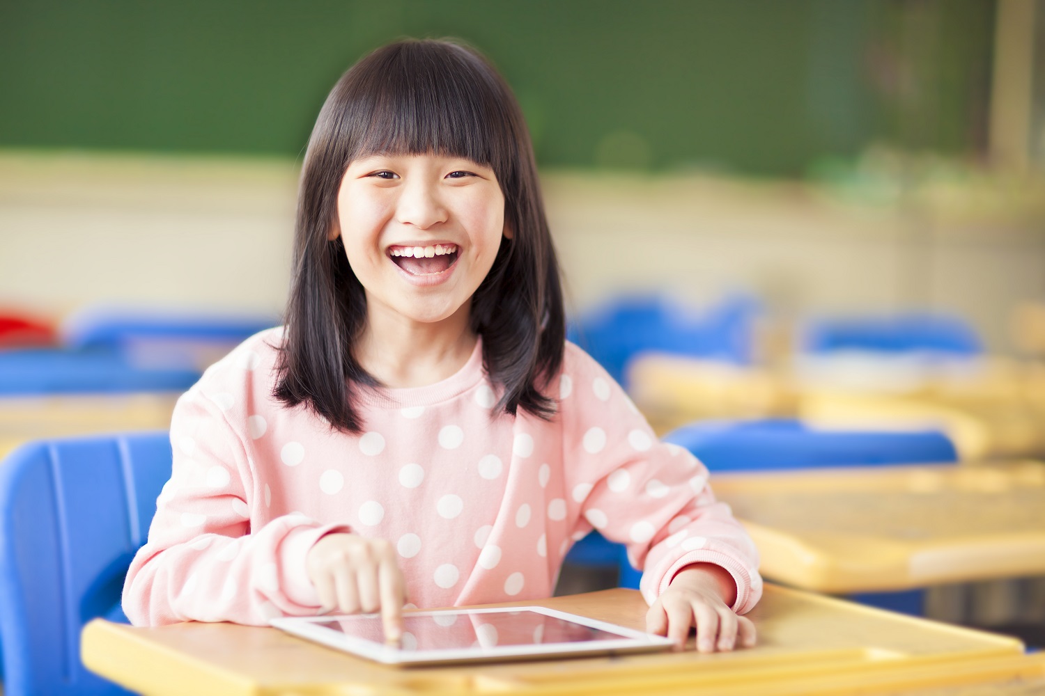 a young girl smiling while using a tablet
