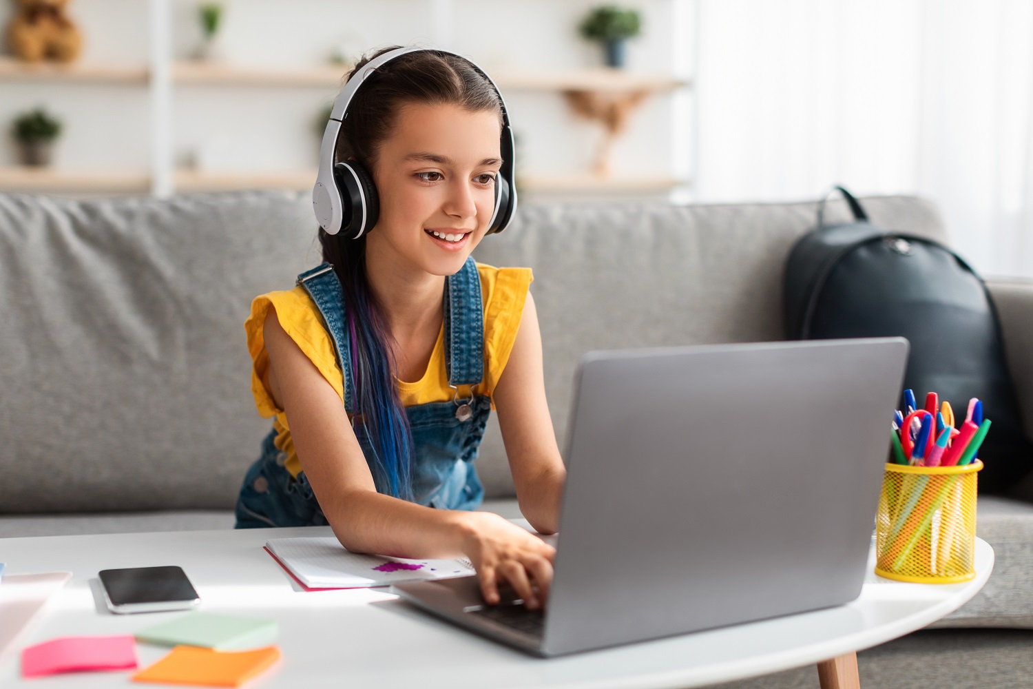 a kid wearing headphones using a laptop