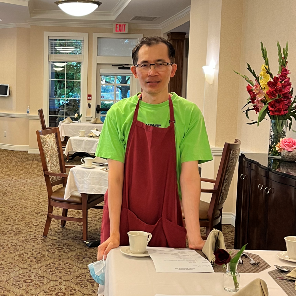Edgardo wearing an apron, leaning against a table in a ballroom