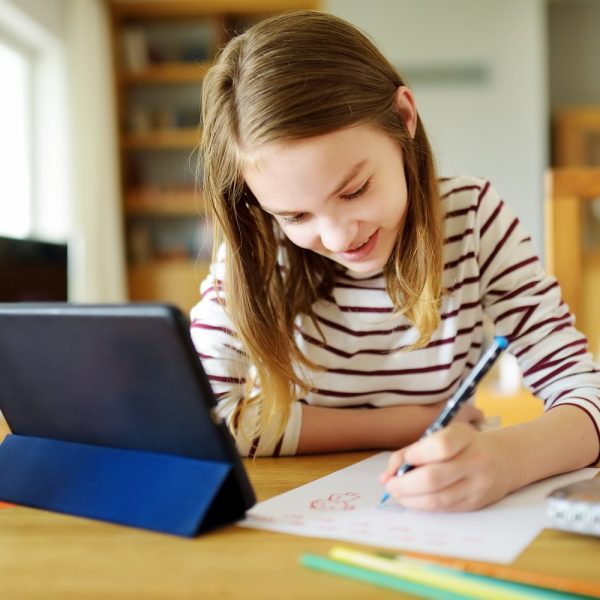 a child does her homework next to a tablet