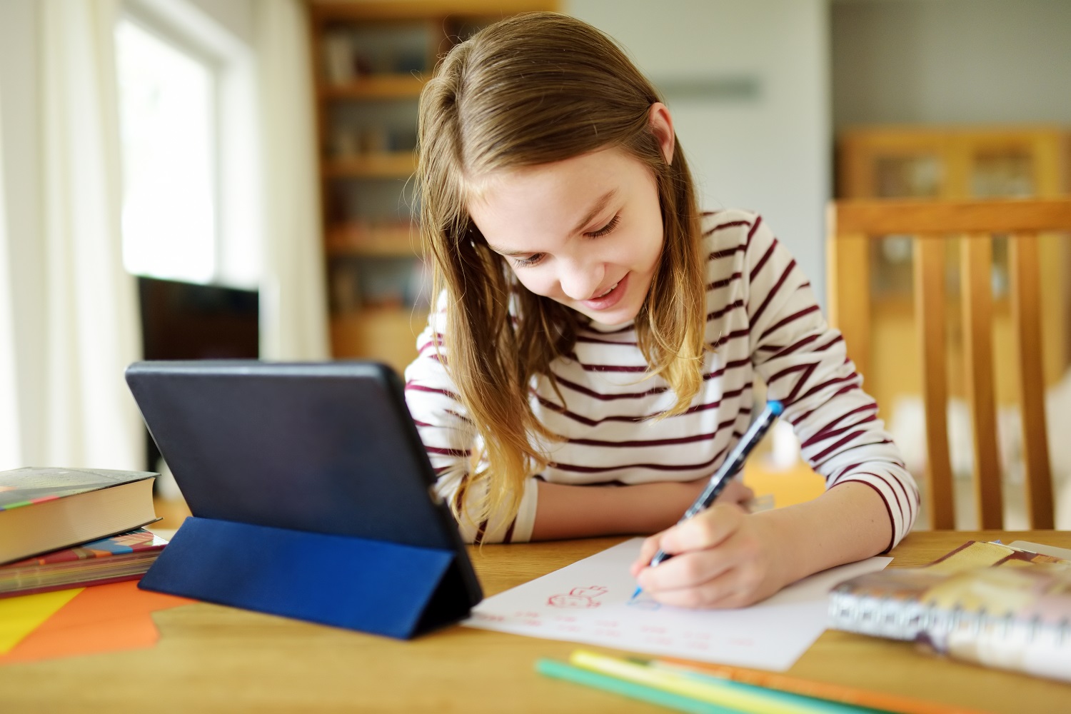 a child does her homework next to a tablet