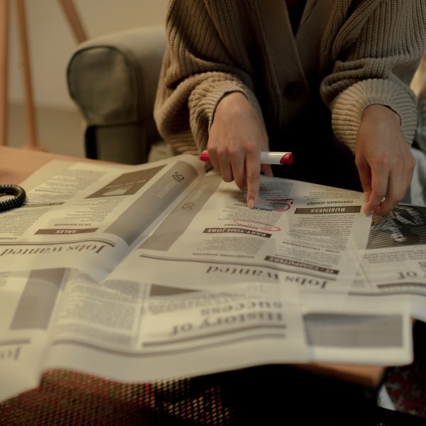 a woman looks through a newspaper for job listings