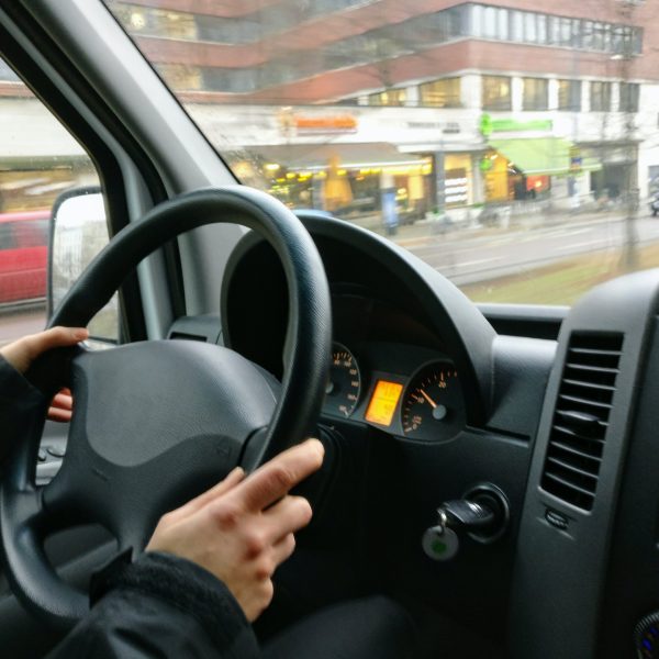 a person holding a steering wheel, driving a bus