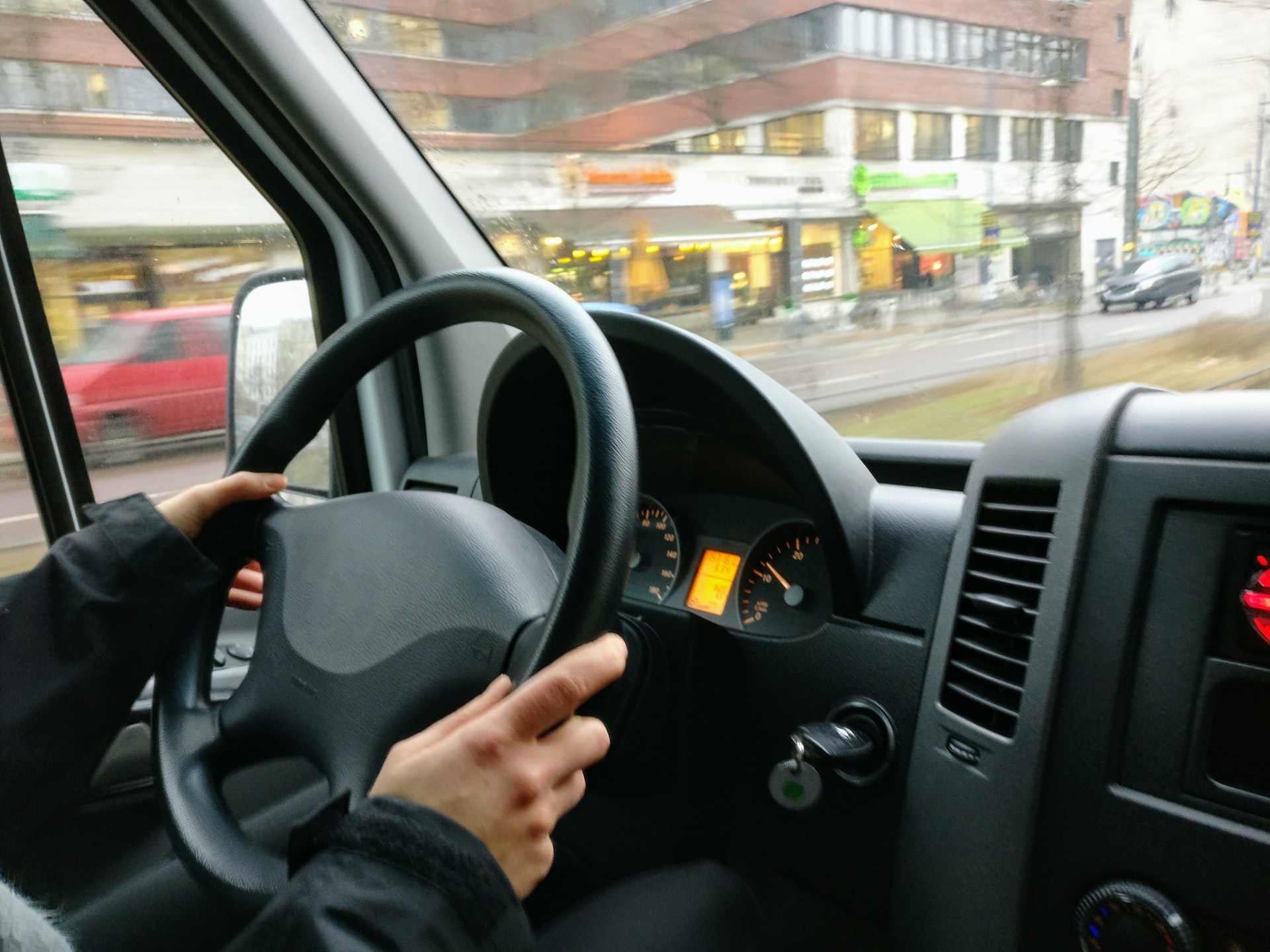 a person holding a steering wheel, driving a bus