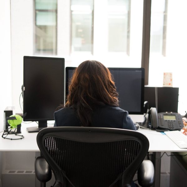 a woman sitting at her desk, looking at her computer