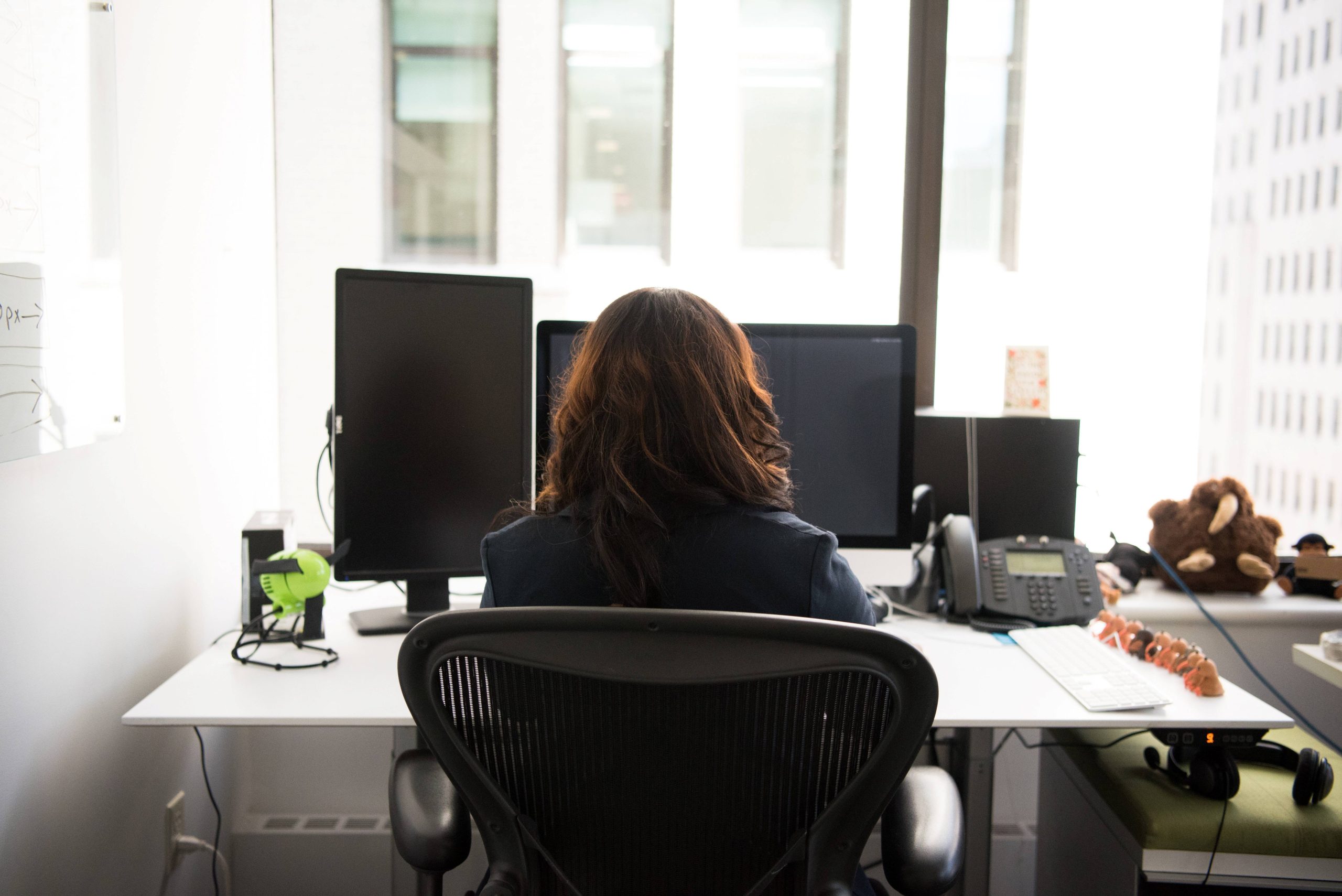 a woman sitting at her desk, looking at her computer