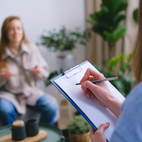 A professional writing a note as she speaks to a client.