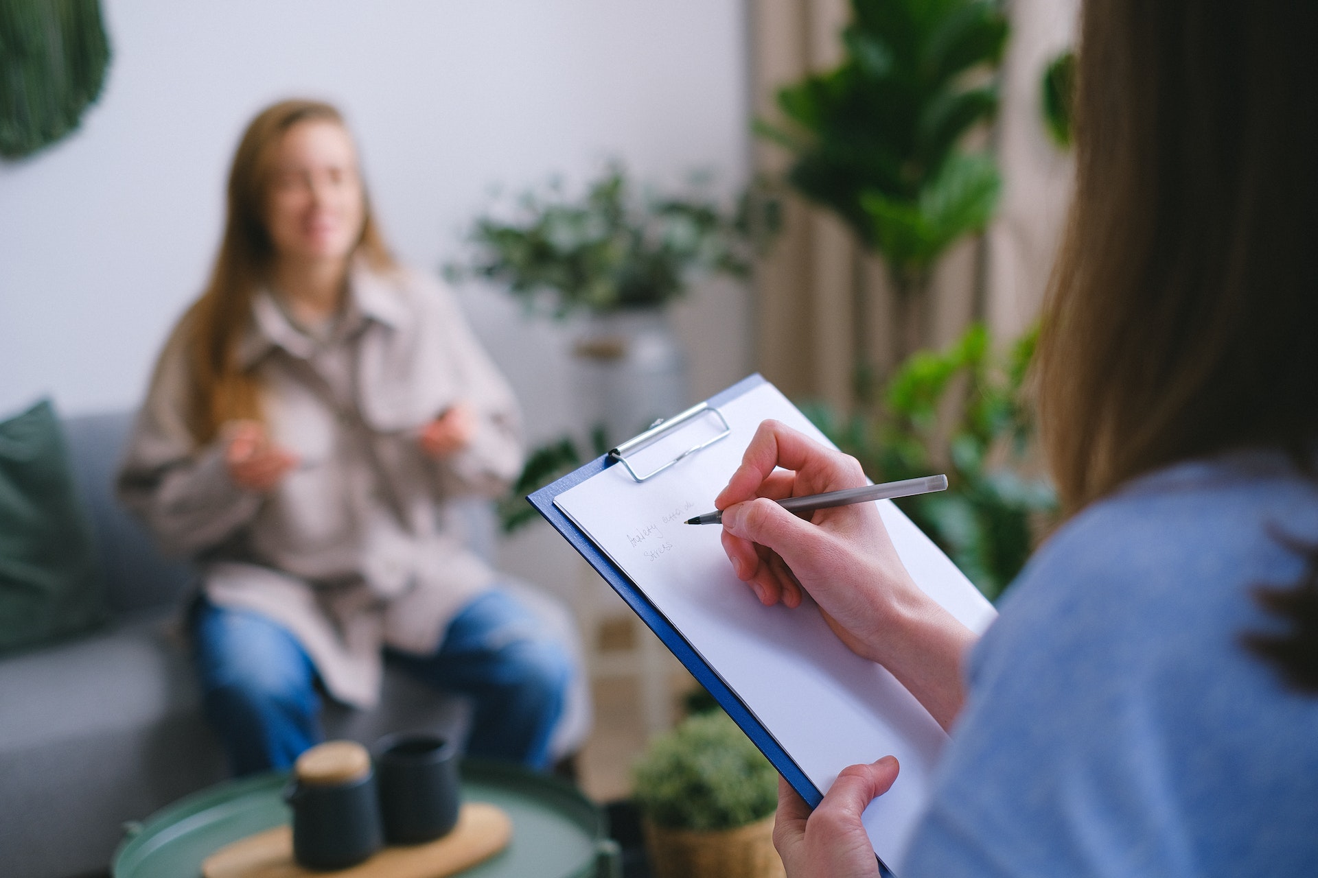 A professional writing a note as she speaks to a client.
