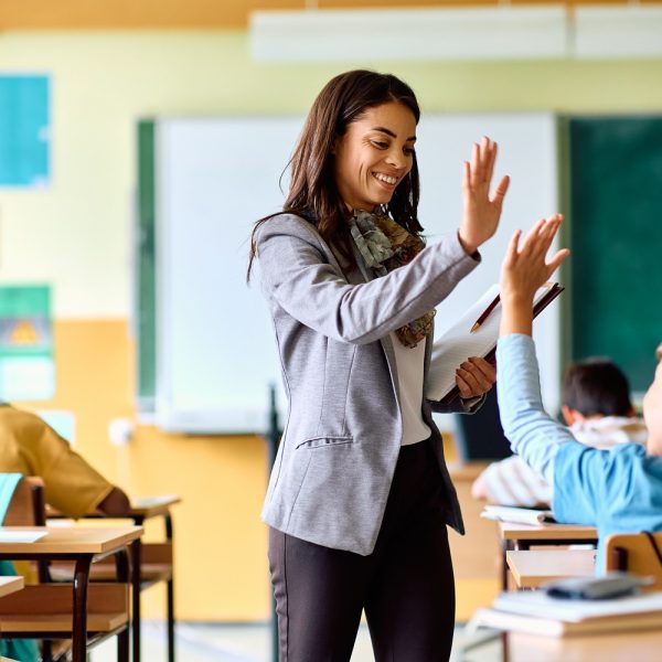 A teacher high-fiving a student in a classroom.