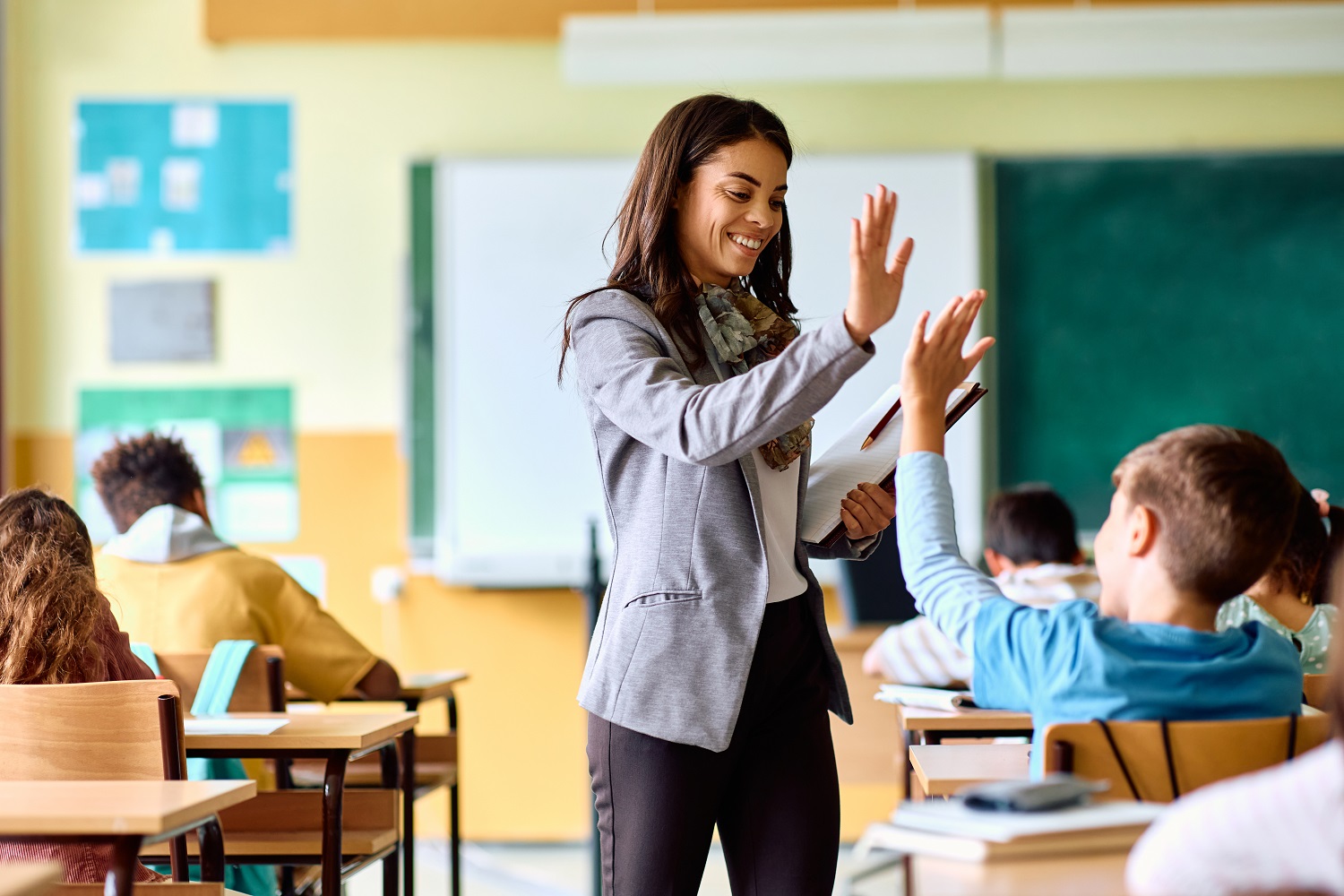 A teacher high-fiving a student in a classroom.