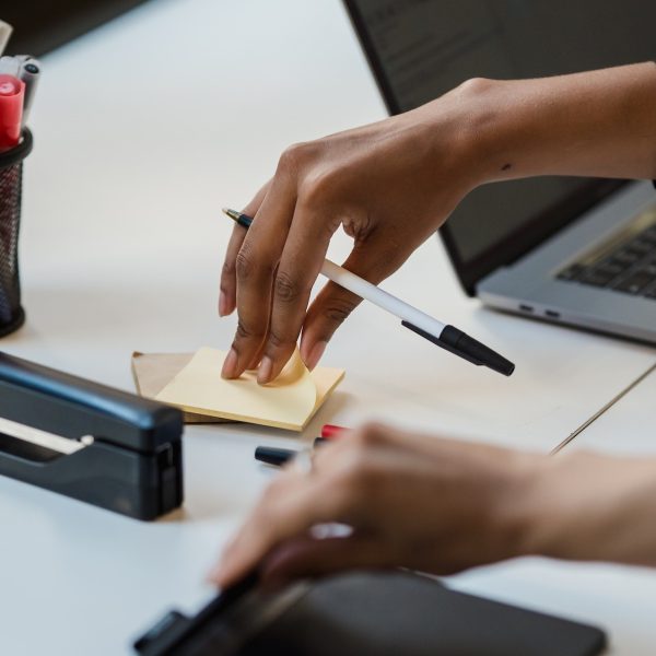 A person tearing a sticky note from a pad on their desk.