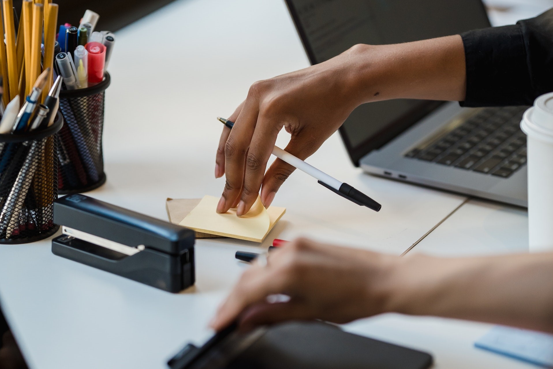 A person tearing a sticky note from a pad on their desk.