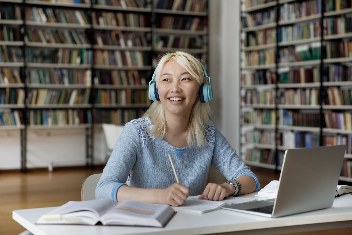 A female student wearing headphones writes in her notebook.