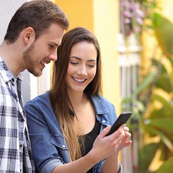 A woman shows a man something on a phone.