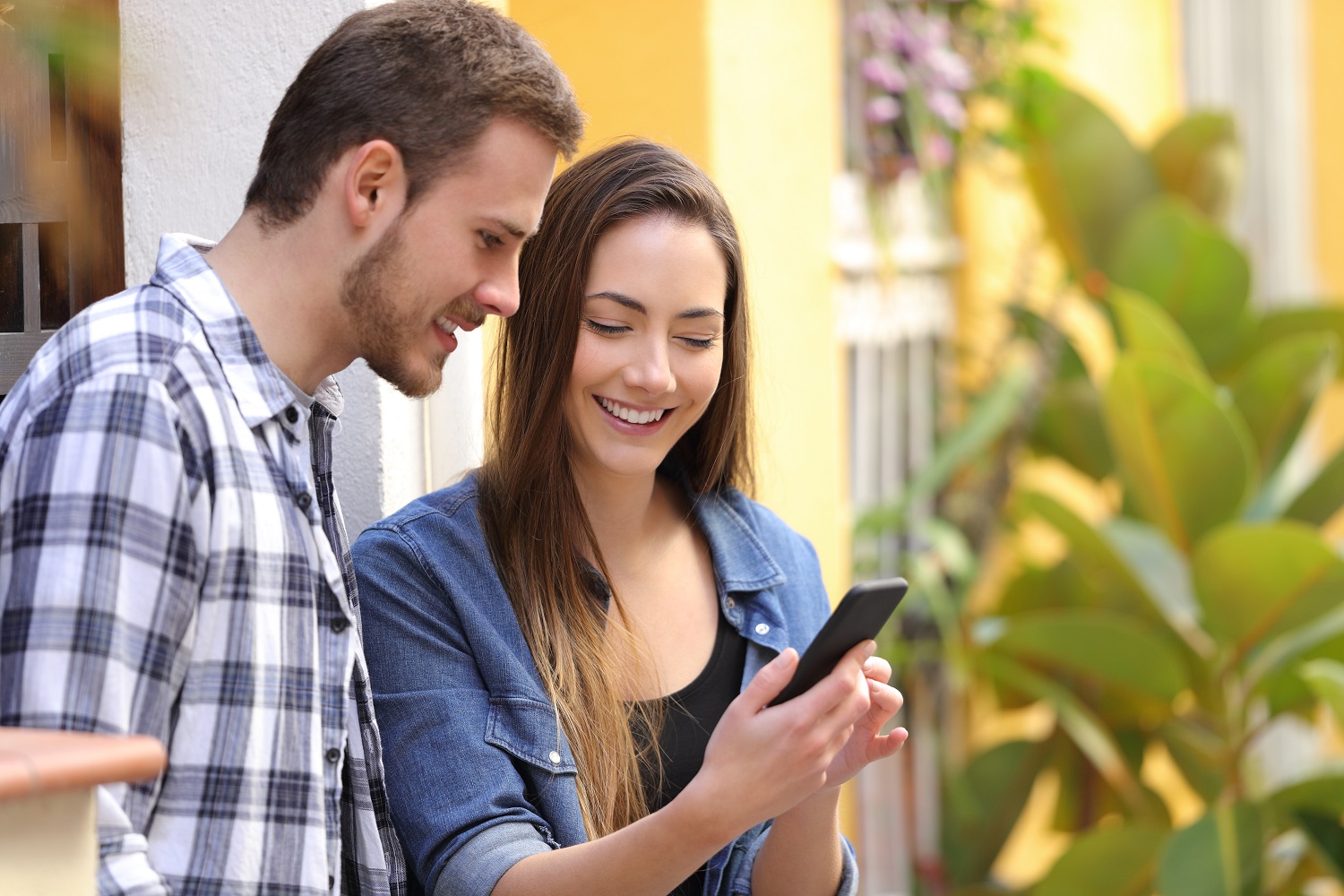 A woman shows a man something on a phone.