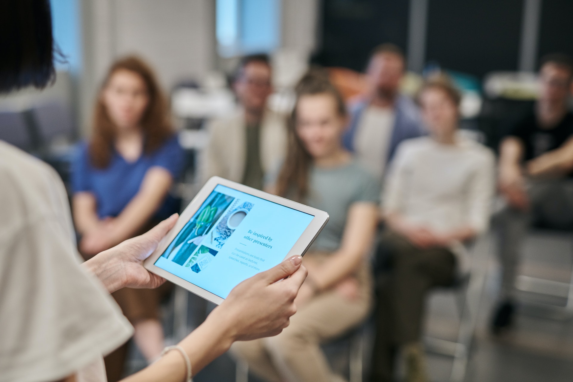 A teacher uses a tablet as she lectures to a class of adults.