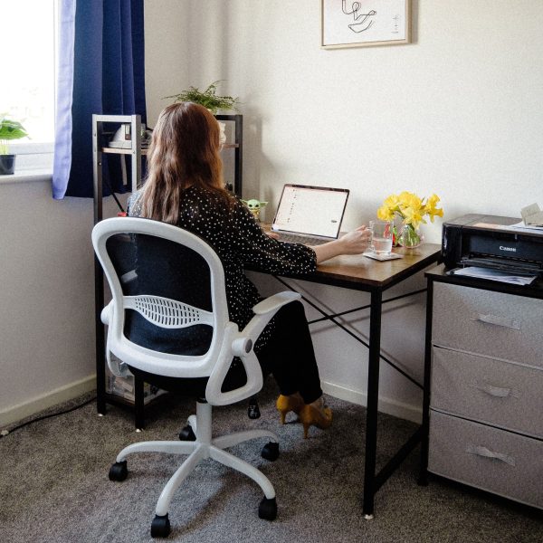 A woman in a comfortable chair uses a laptop.