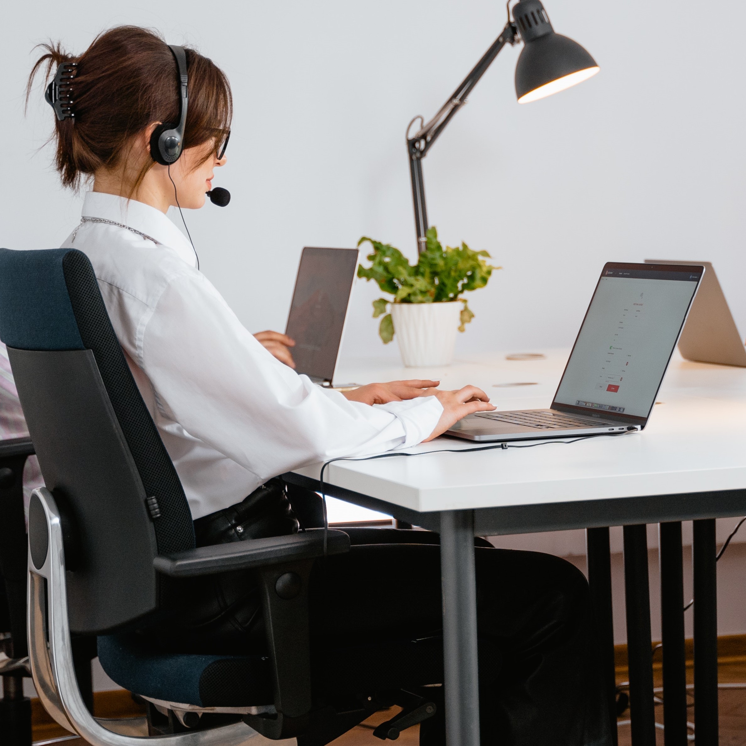 A woman talking on a headset in a call centre-like setting.