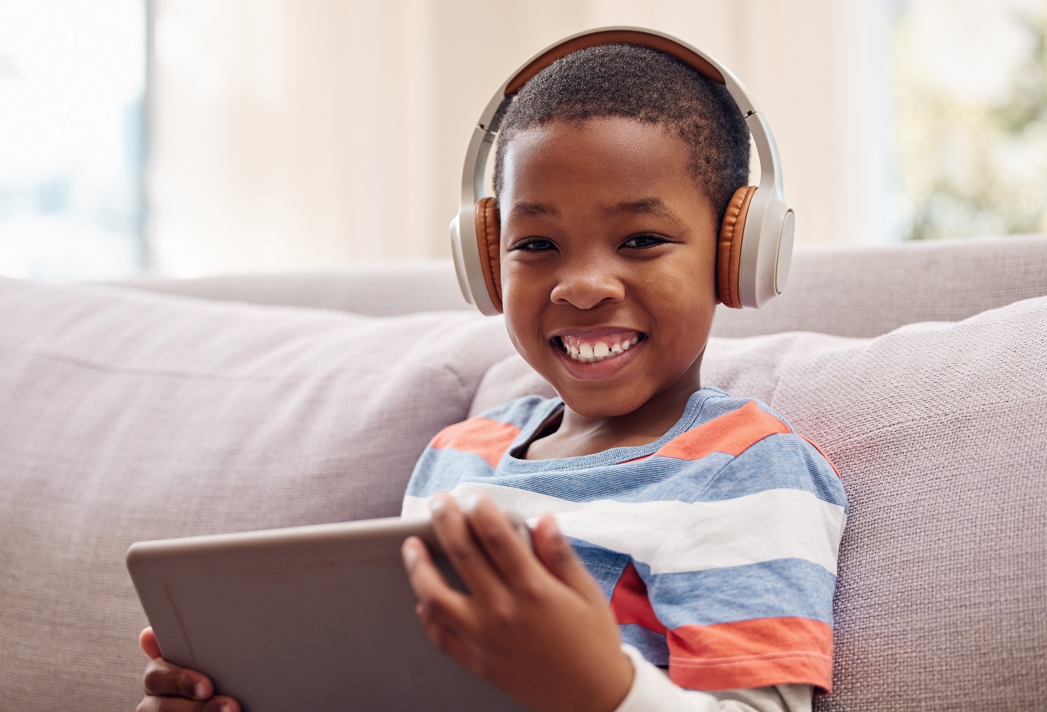 A young boy using a digital tablet while relaxing at home.