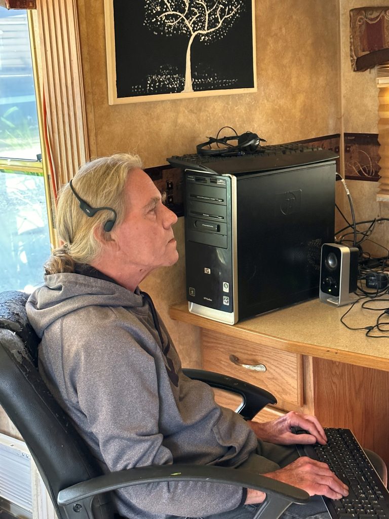 Rob wearing a headset and using a computer in his home office.