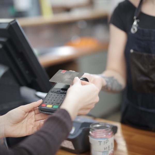 A customer pays with their credit card as a cashier watches at a grocery till.