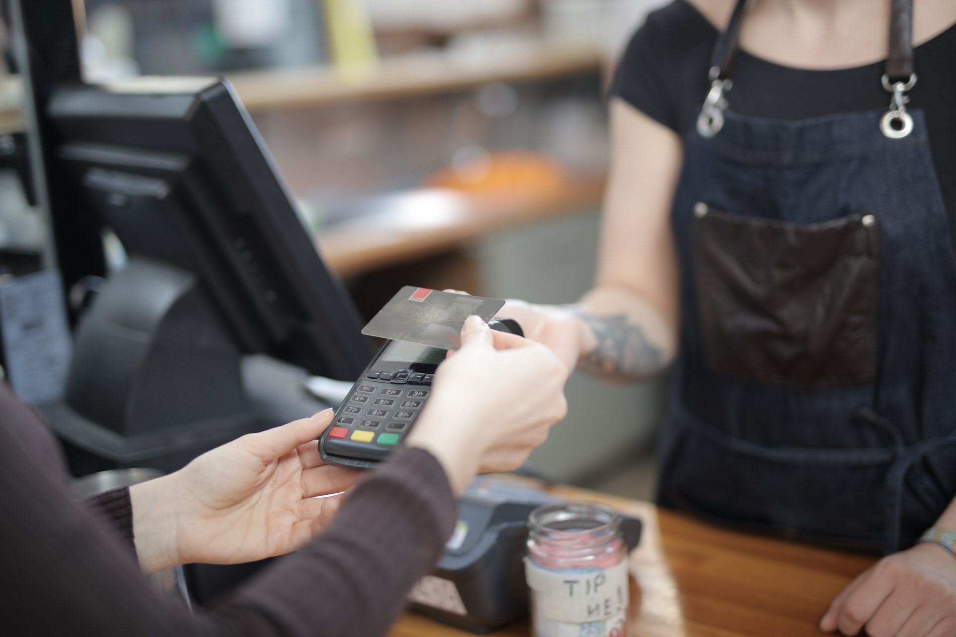 A customer pays with their credit card as a cashier watches at a grocery till.