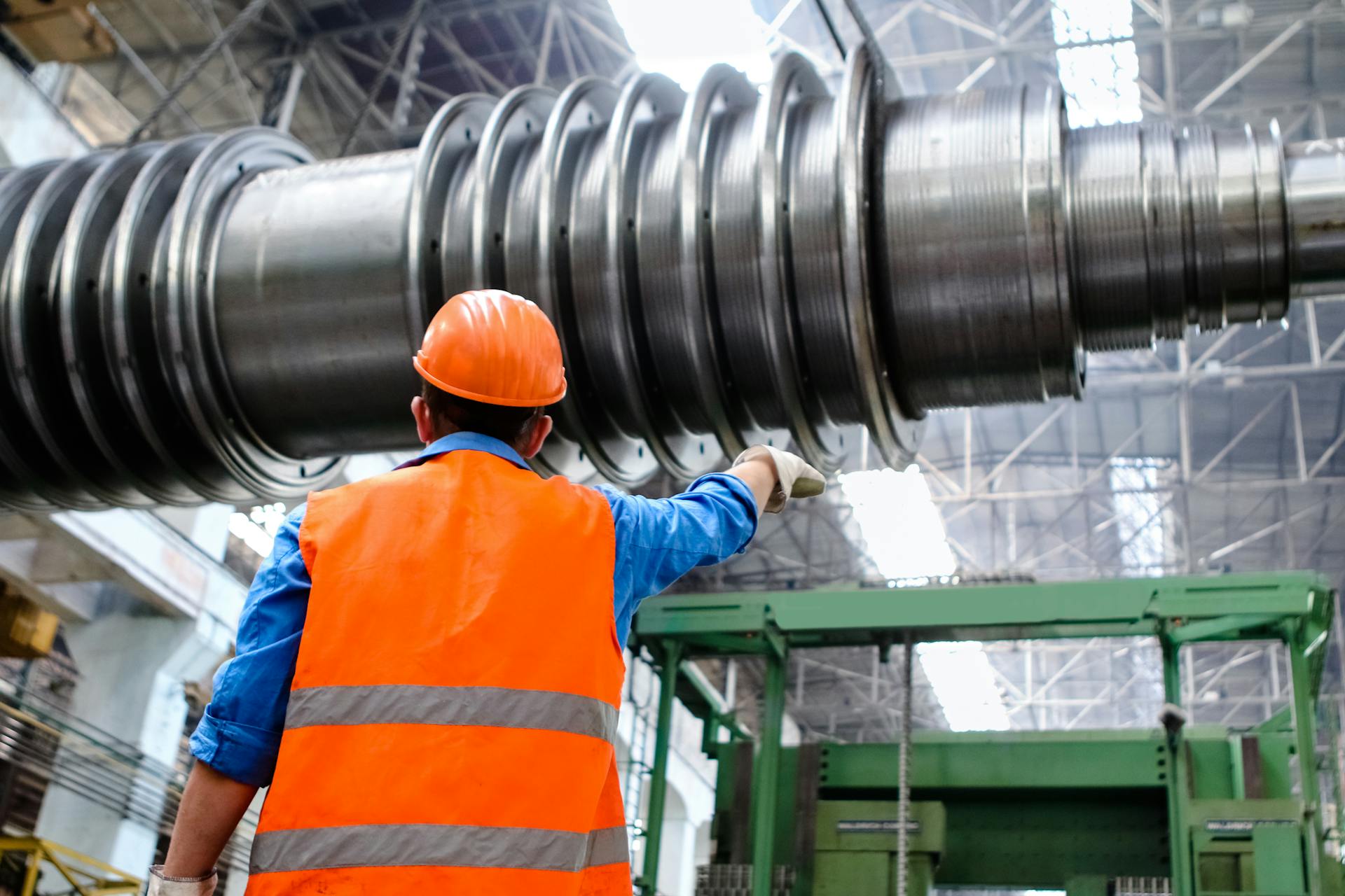 An engineer wearing a high visibility vest overlooks a giant pipe being fitted on a construction site.