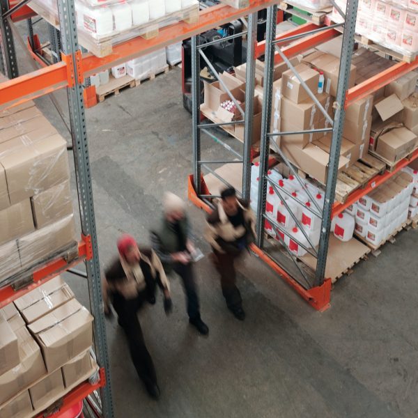 Three workers walk in a warehouse.