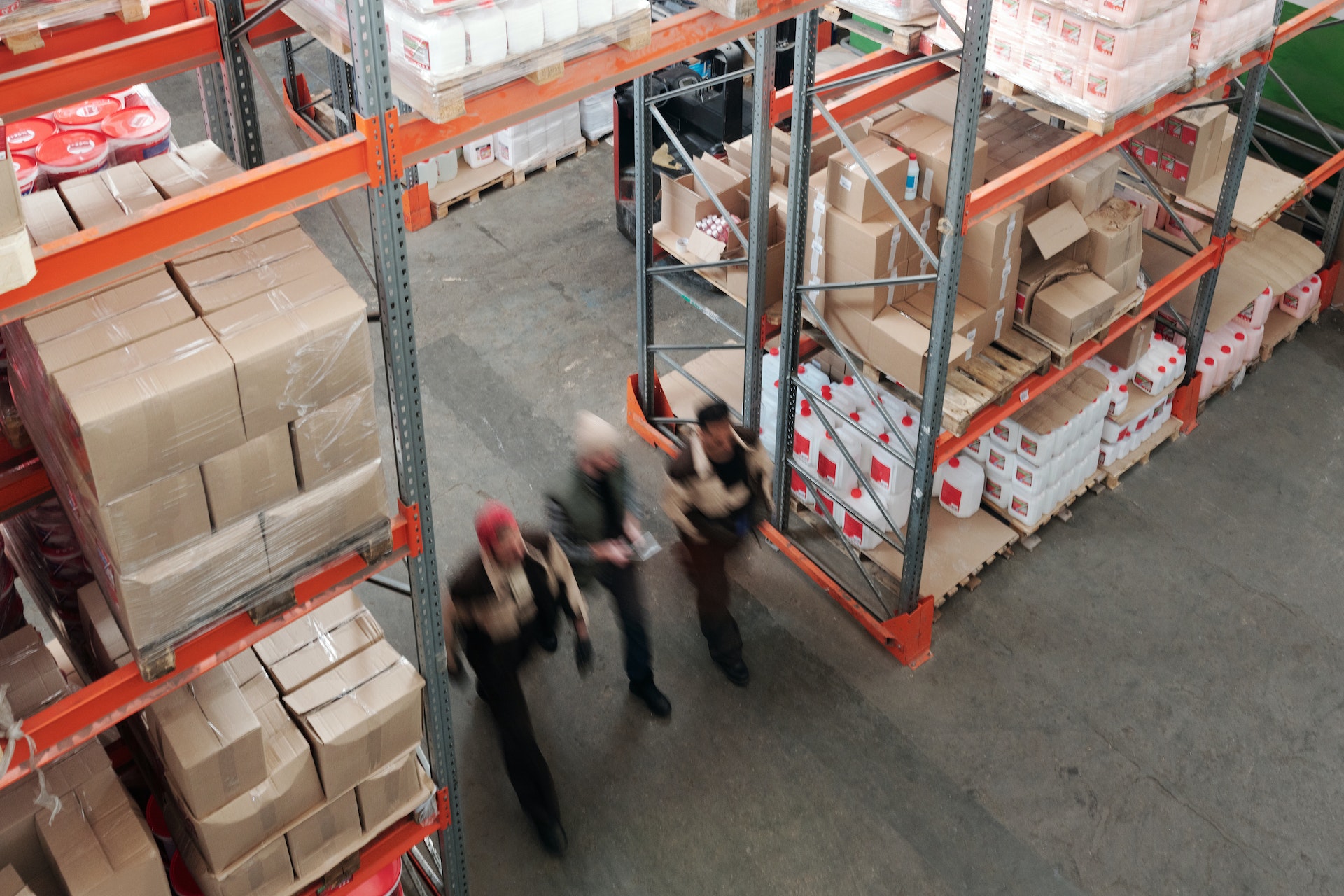 Three workers walk in a warehouse.