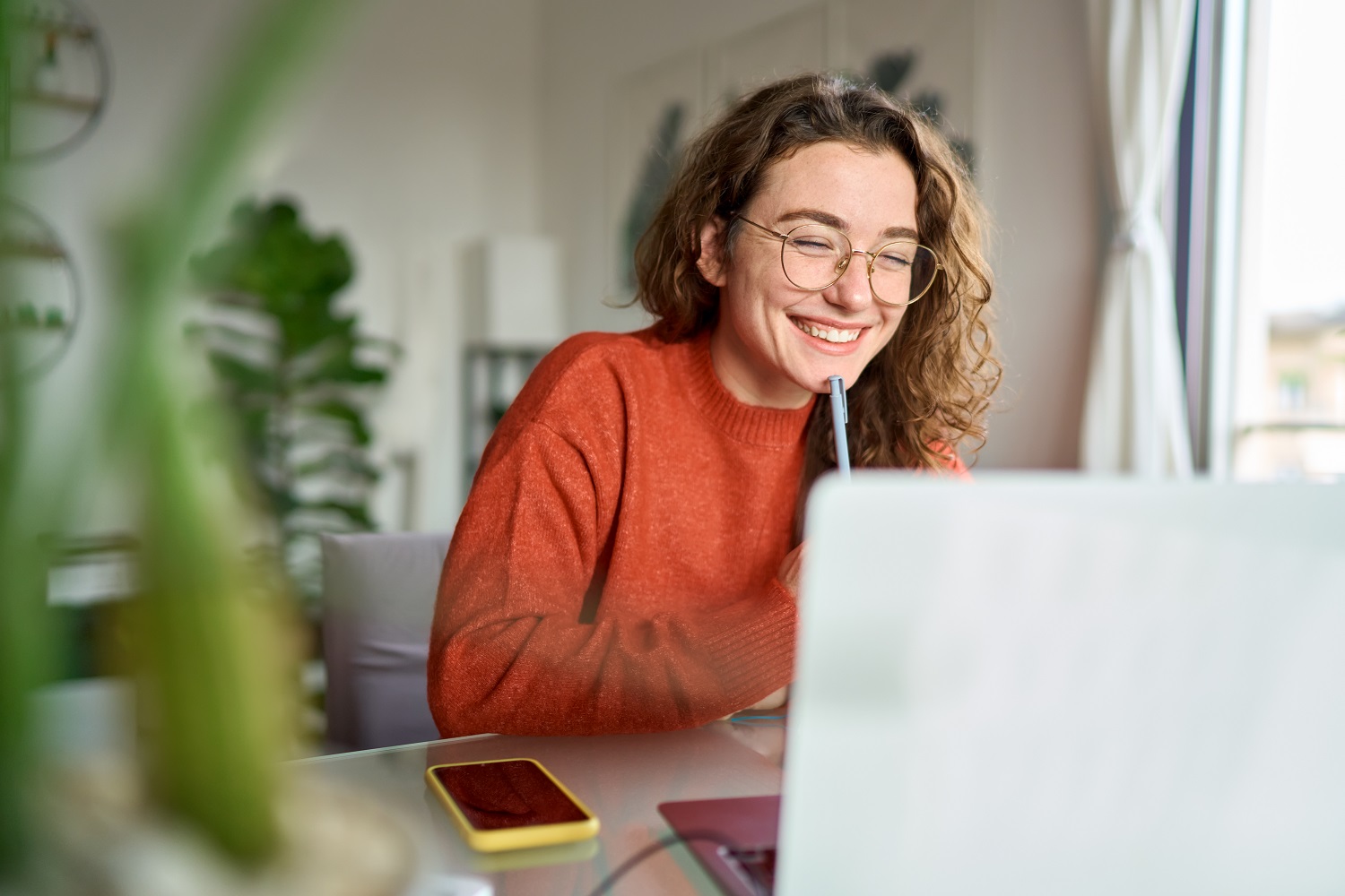 A woman uses a laptop, while writing down notes.