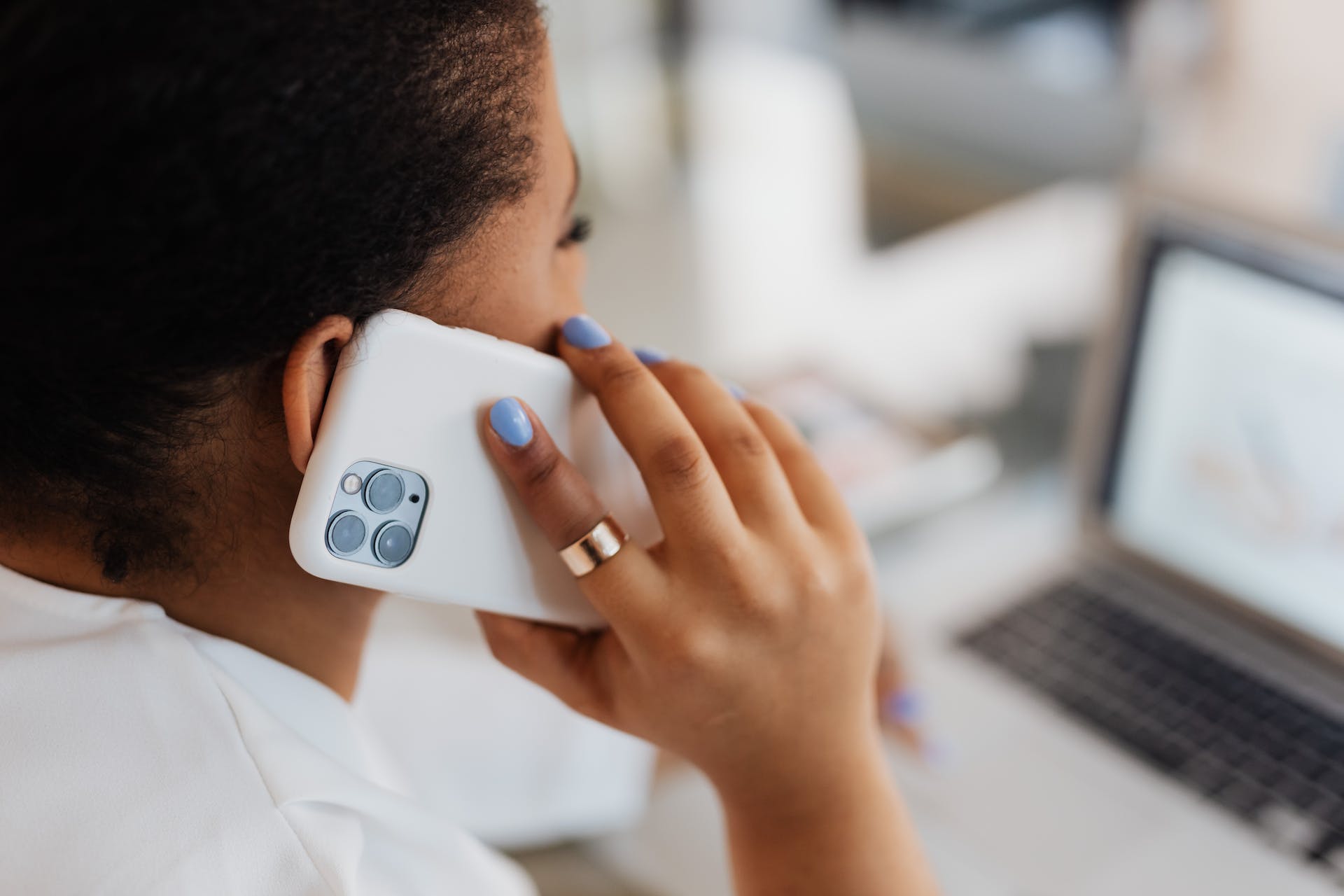 A woman talks on her phone at her desk.