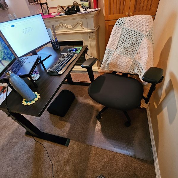 Michelle's workstation, featuring her adjustable chair, sit/stand desk, laptop riser, monitor, and other ergonomic supports.