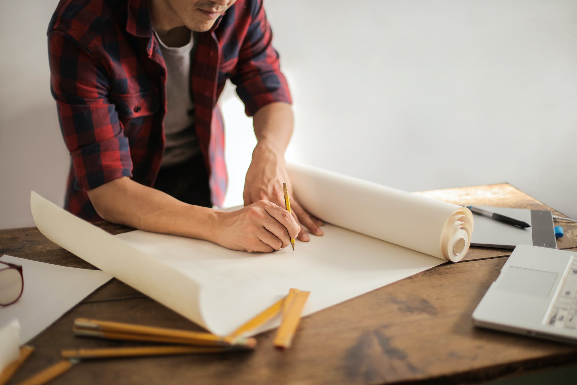 A man draws with a pencil on some plans.