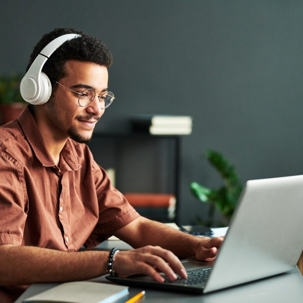 A man wearing a headset uses a laptop.