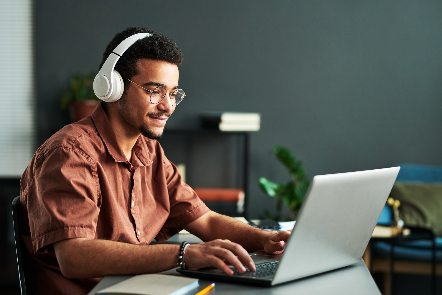 A man wearing a headset uses a laptop.