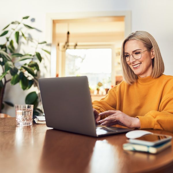 A woman smiles while using a laptop.