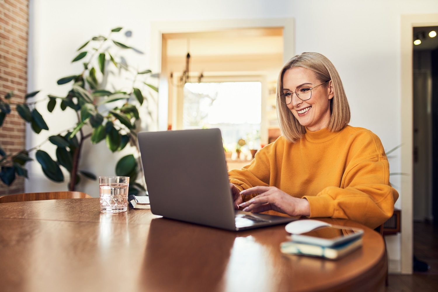 A woman smiles while using a laptop.