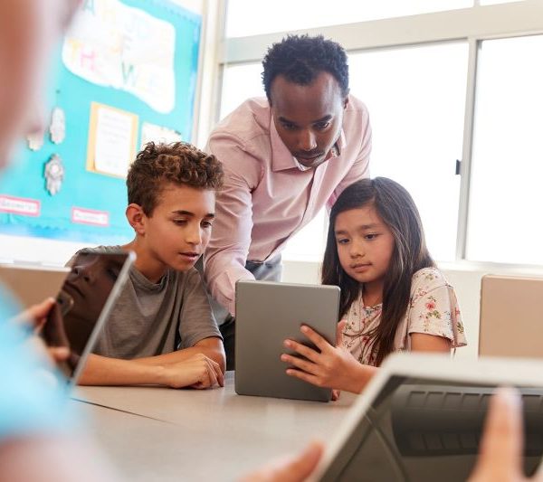 A teacher demonstrates a concept to students using a tablet.