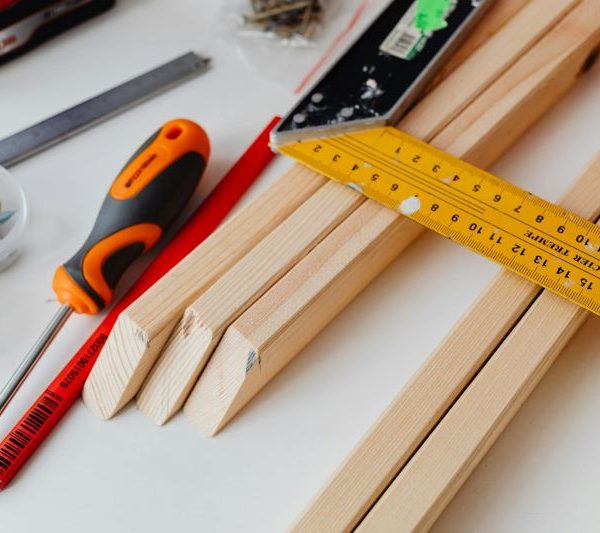 various building supplies including wood, a screwdriver, a ruler, a pencil, and screws
