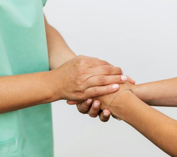 A person wearing a medical outfit holding another person's hand.
