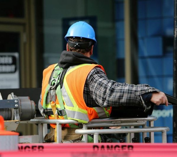 A man wearing a high vis vest and a hard hat at a construction site.