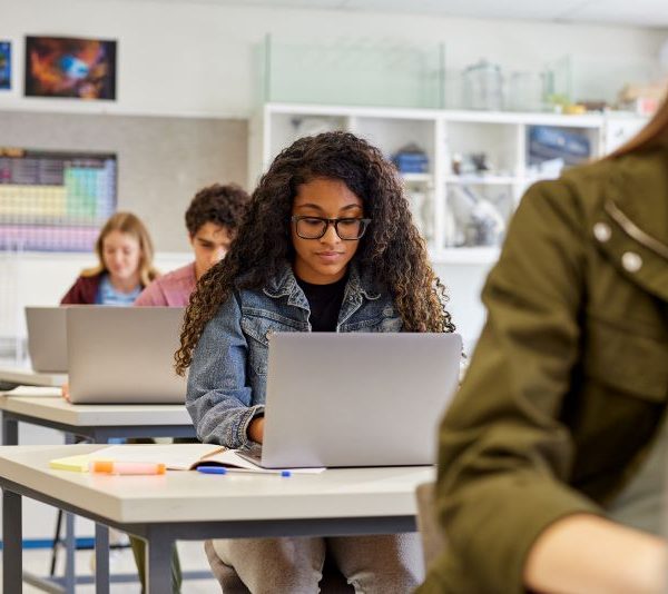 A woman in a classroom goes on laptop.