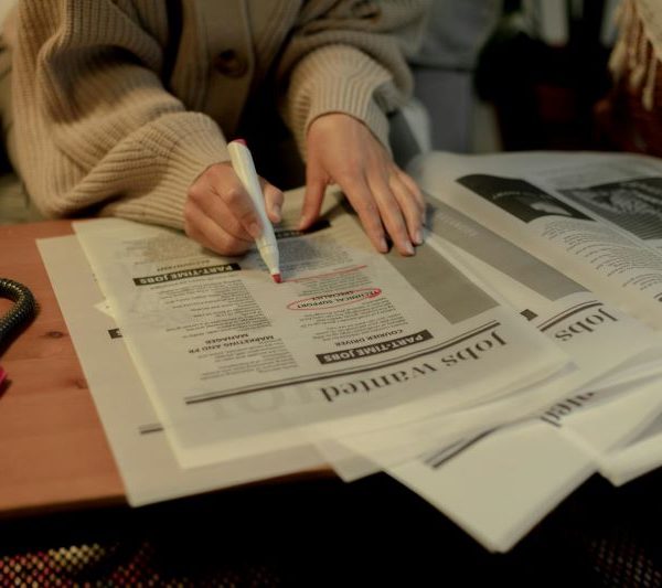 A person circles a classified ad in a newspaper.