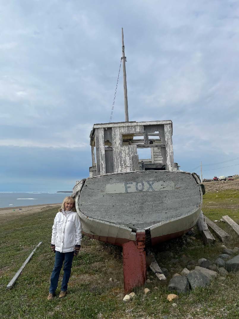 Susan standing near a beached boat on a beach.
