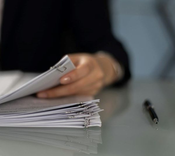 A person goes through paperwork on their desk.