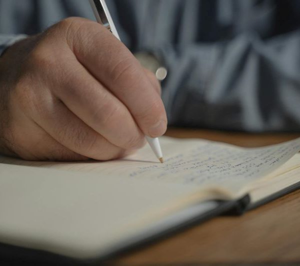 A man writes into a notebook.