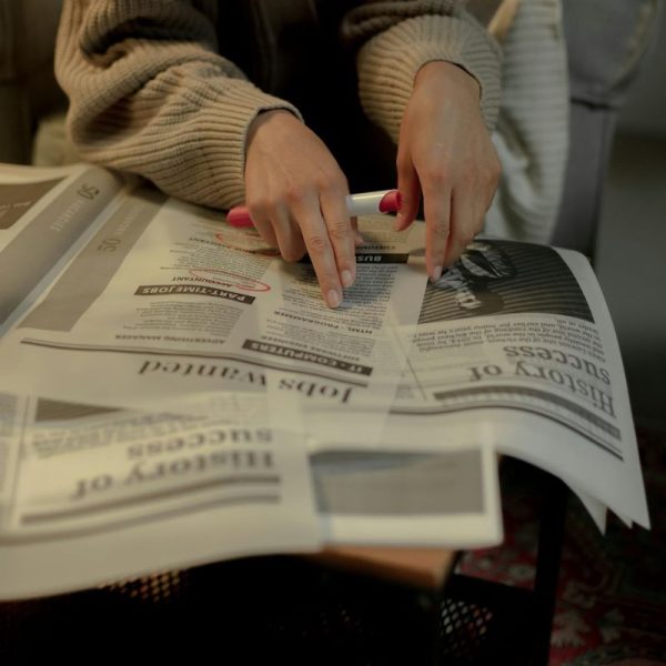 A person looks for work in the classified ads in the newspaper.