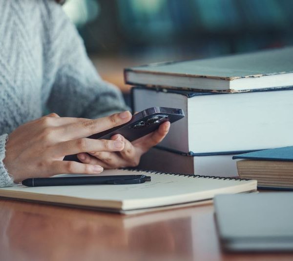 A person uses a smartphone while studying at a library.