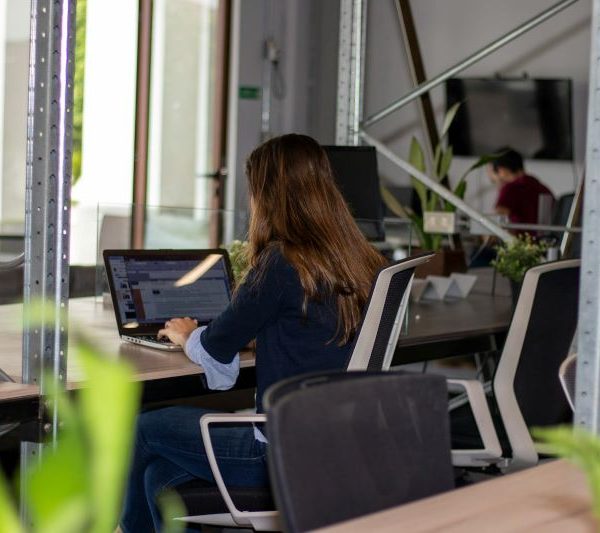 A woman works on a laptop in an office.